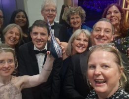 A photograph of several members of the DanceSyndrome team at an awards ceremony. Our Founder Jen Blackwell is at the front holding up a trophy.