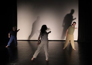 Three dancers with a bright light casting strong shadows