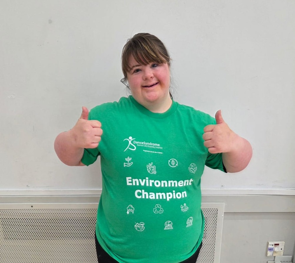 A picture of Lucy wearing a green t-shirt that says "Environment Champion" with her thumbs up.