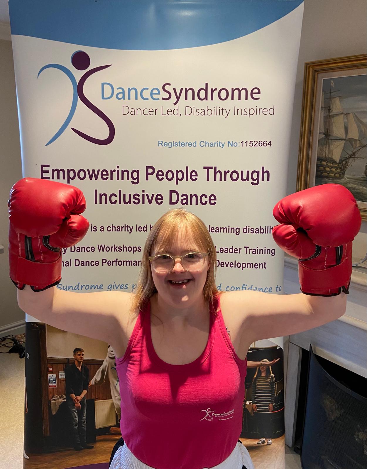 A picture of Becky wearing boxing gloves with her arms raised